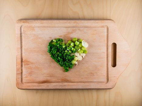 Heart shaped pile of bunching onion on the wooden board, from the top view, healthy life style