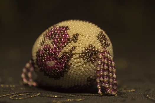 Easter Egg embroidered with colorful beads on a dark premise