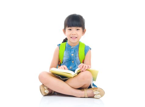 Asian preschool girl with schoolbag and books sitting on the floor