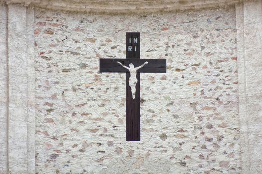 Black cross with Jesus hanging on the stone wall