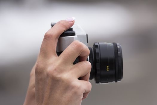 girl with a nice manicure holding vintage camera in the hands of