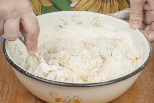 Women's hands preparing fresh yeast dough.