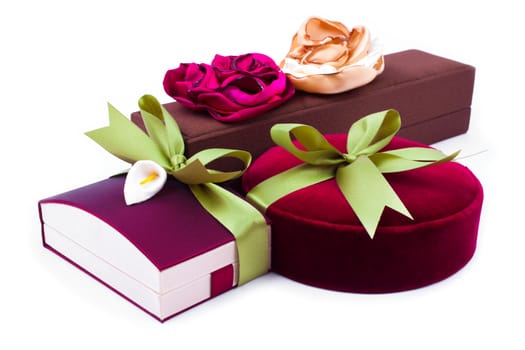 Luxury gift boxes in dark red and brown shades with green satin ribbon and bow isolated over white background.