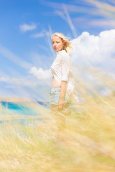 Relaxed woman enjoying freedom and life an a beautiful sandy beach.  Young lady feeling free, relaxed and happy. Concept of freedom, happiness, enjoyment and well being.  Enjoying Sun on Vacations.