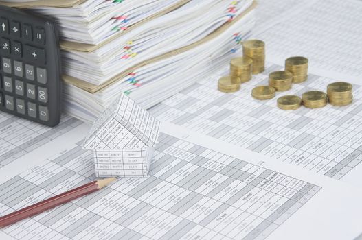 House and brown pencil on finance account have blur step pile of gold coins and calculator place vertical beside overload of paperwork and brown envelope with colorful paperclip as background.