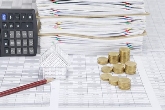 House and brown pencil with step pile of gold coins on finance account have calculator place vertical beside overload of paperwork and brown envelope with colorful paperclip as background.