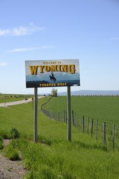 Welcome to Wyoming state sign  with the Wyoming landscape of open plains and mountains in the background.