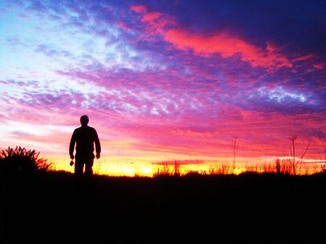 A man carrying a camera into a dawn sky