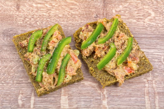 Raw bread with a spread decorated with green pepper