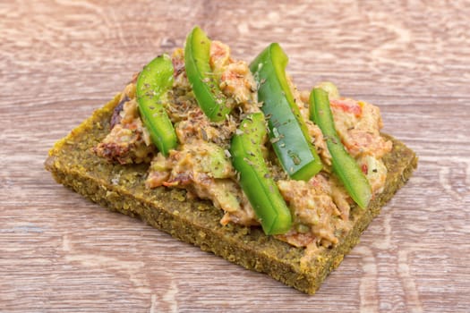 Raw bread with a spread decorated with green pepper