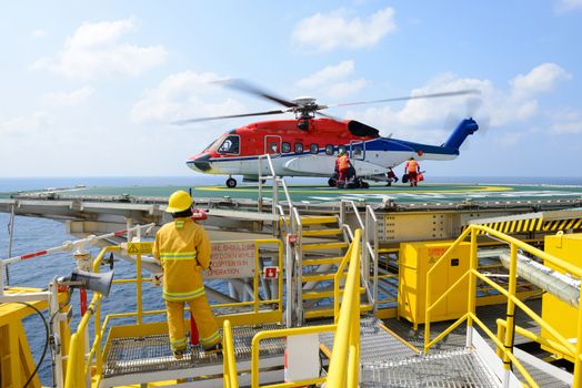 The landing officer are loading baggage of passenger to helicopter at oil rig platform