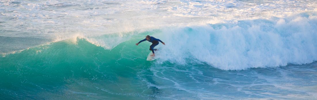 La Pared, Spain - Dec 23, 2015:  Active sporty senior surfer riding perfect wave on La Pared beach, famous surfing destination on Fuerteventura, Canary Islands, Spain on December 23, 2015. 