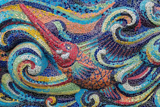 Colorful glass mosaic art shape fish and abstract wall background.