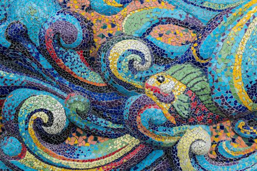 Colorful glass mosaic art shape fish and abstract wall background.