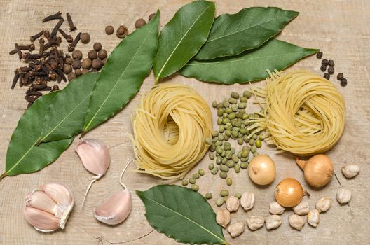 Not the cooked pasta, Bay leaf, onion, garlic and other spices on the old wooden background