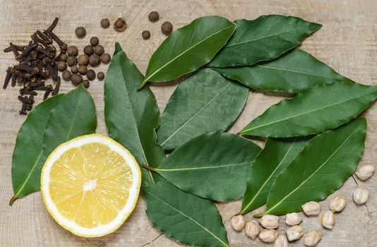 A half of a lemon and spices, lying on the old Board. Bay leaves and pepper with the cloves.