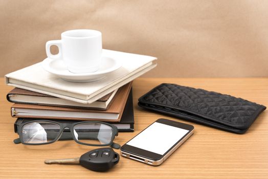 coffee and phone with stack of book,car key,eyeglasses and wallet on wood background