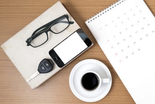 coffee and phone with car key,eyeglasses,stack of book,calendar on wood background