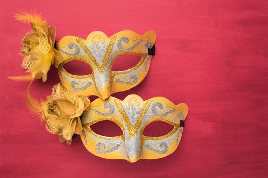 Colorful carnival mask on a red textured background. Masks with theater concept. Top view with copy space