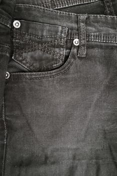 Closeup detail of black denim jeans trousers pocket, texture background. Top view with copy space