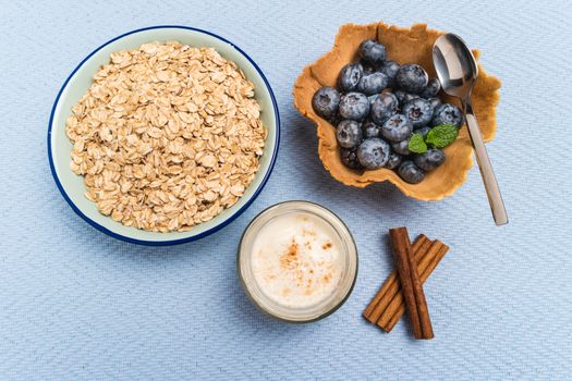 Waffle with blueberries and mint leaf. Yogurt with cinnamon and bowl of oatmeal  on rustic textured background. Top view with copy space.
