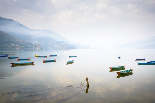Boats on Phewa Lake in Pokhara, three sunken ones in the foreground, Nepal.