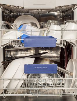 Utensils in dishwasher, washed cups and plates