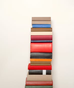 Stack of old colorful books  near the white wall