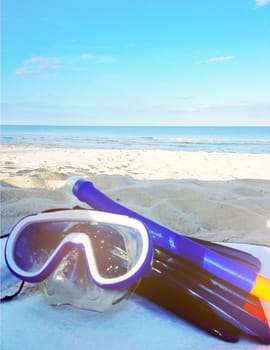 Diving goggles,snorkel on sand beach with sunlight