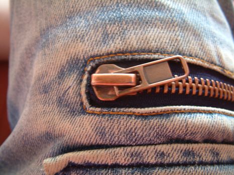 A zipper on a blue and worn denim material