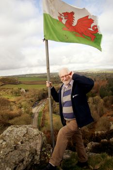A man placing the Welsh flag atop a Welsh mountain
