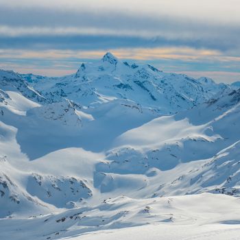 Snowy blue mountains in clouds. Winter ski resort