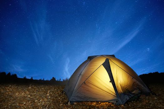 Illuminated yellow camping tent under stars at night