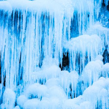 Frozen waterfall of blue icicles on the rock