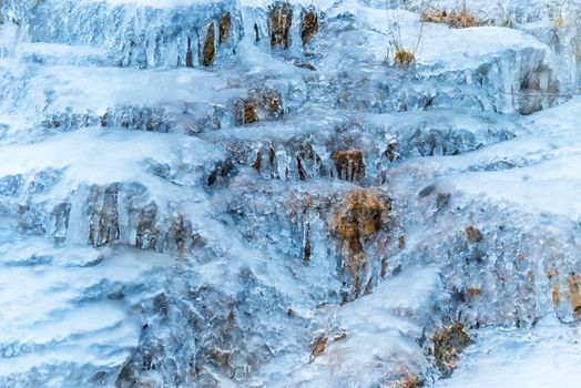 Frozen waterfall of blue icicles on the rock