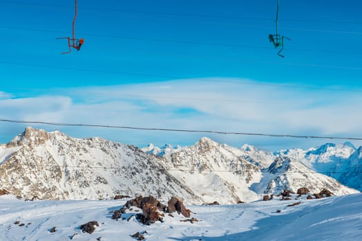 Cableway in snowy blue mountains with clouds. Winter ski resort