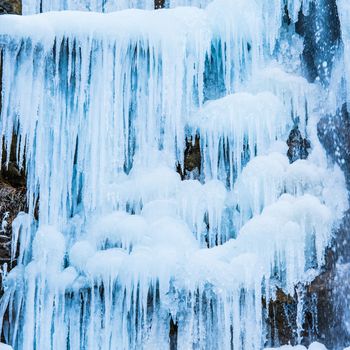 Frozen waterfall of blue icicles on the rock