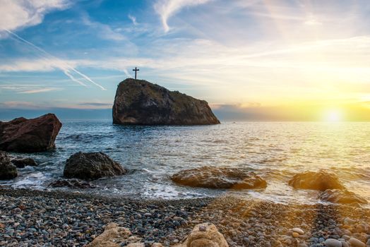 Sunset on the beach with sea, rocks and dramatic sky