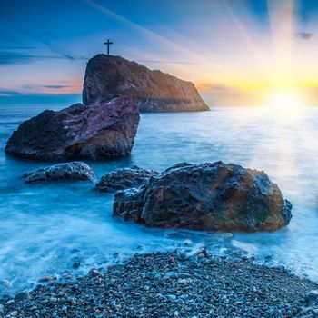 Sunset on the beach with sea, rocks and dramatic sky