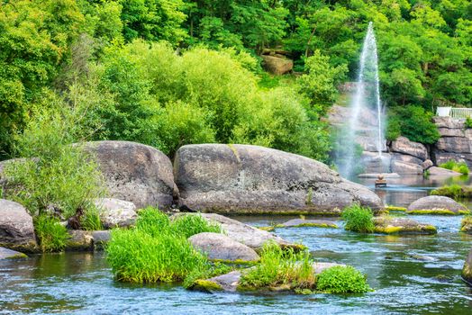 Fountain in the lake between tropical forest. Environment sunny landscape