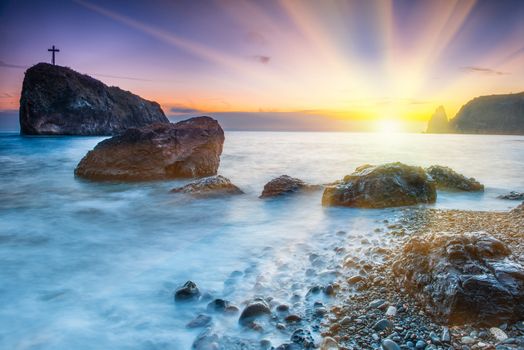 Sunset on the beach with sea, rocks and dramatic sky. Seaside landscape