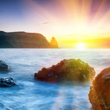 Sunset on the beach with sea, rocks and dramatic sky