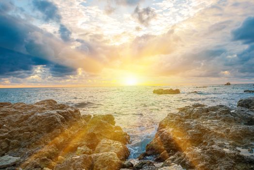 Sunset on the beach with waves, sea, rocks and dramatic sky