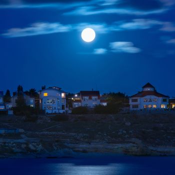 Moon over the river by the town with blue sky and clouds