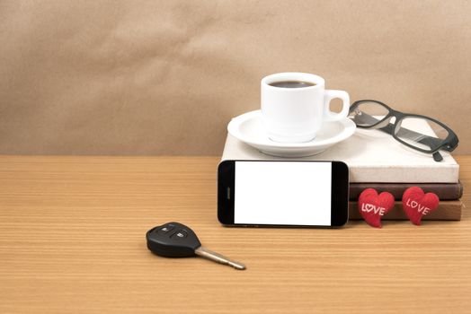 office desk : coffee and phone with car key,eyeglasses,stack of book,heart on wood background