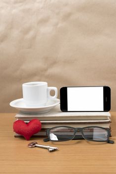 office desk : coffee and phone with key,eyeglasses,stack of book,heart on wood background