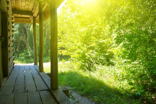 Old wooden house in the green forest. Sunny day in a village