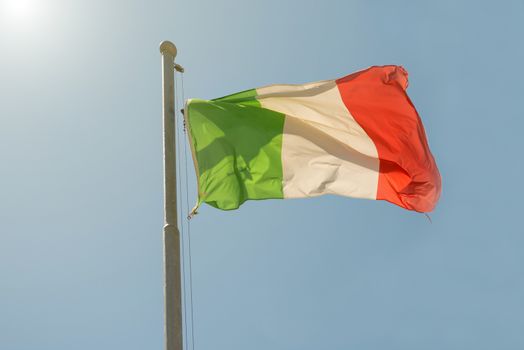 Waving Italian flag on the blue sky background