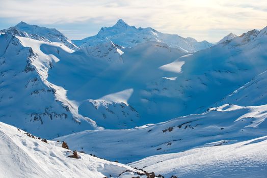 Snowy blue mountains in clouds. Winter ski resort