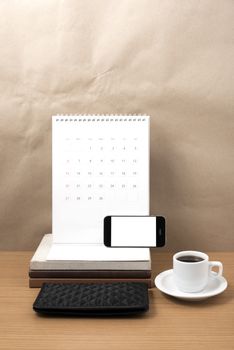 working table : coffee with phone,stack of book and wallet on wood background